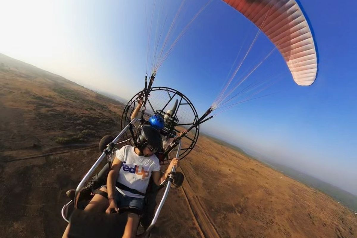 Paramotor flying over lush palm trees in Goa