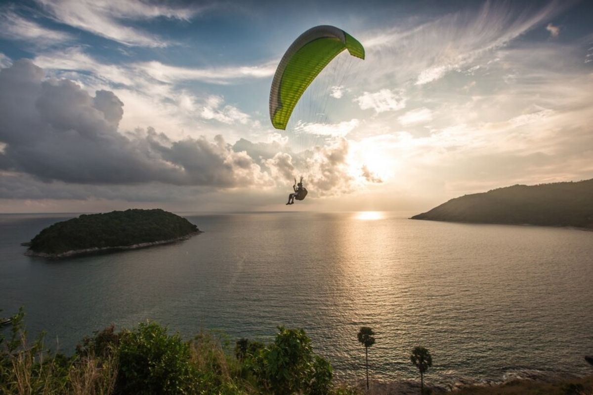 Paramotoring in Goa: A paramotor soaring over golden beaches and turquoise waters of the Arabian Sea during a vibrant sunset, showcasing the thrill and beauty of adventure sports in Goa.