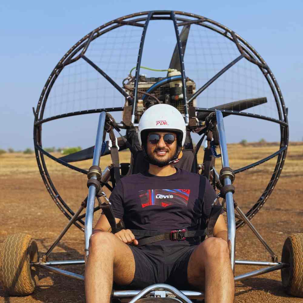 Paramotoring safety: A paramotor pilot flying above golden beaches and the Arabian Sea, highlighting the controlled and scenic nature of paramotoring as an adventure sport