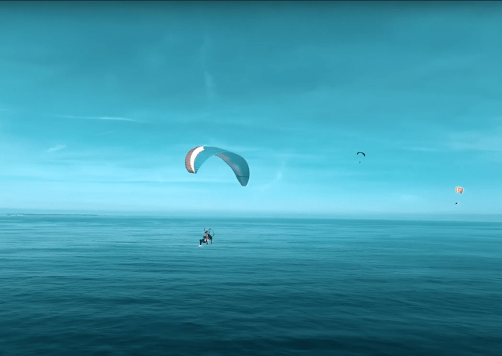 multiple paramotor in the blue sky above the ocean