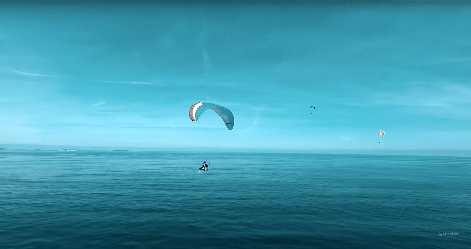 multiple paramotor in the blue sky above the ocean