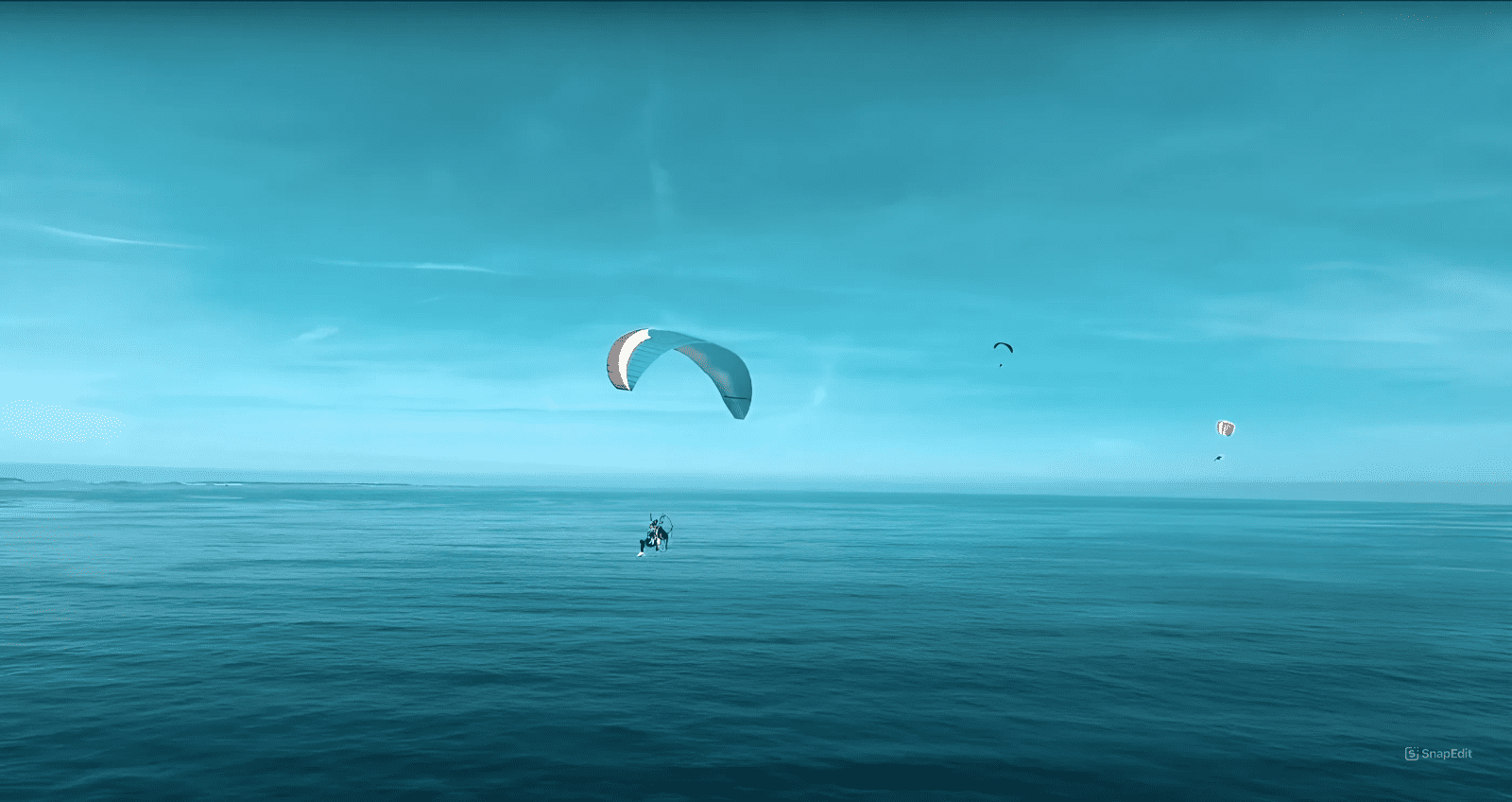 multiple paramotor in the blue sky above the ocean
